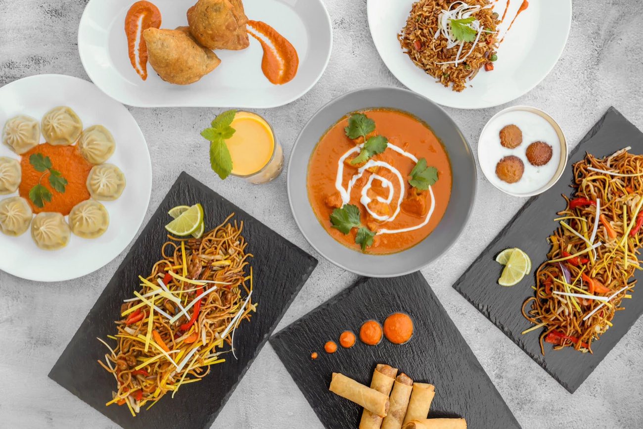 Udvalg af momo, curry, chow mein og samosas serveret til deling